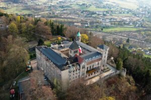 Aerial view of Lesna Skala Castle on forested hilltop overlooking valley