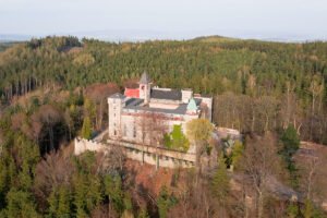 Aerial view of Lesna Skala Castle atop wooded hill