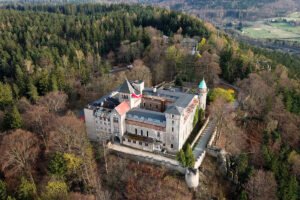 Aerial view of Lesna Skala Castle perched on rocky forested hilltop