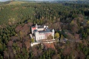 Aerial view of Lesna Skala Castle atop wooded ridge