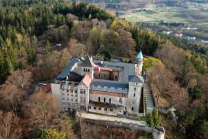 Aerial view of Lesna Skala Castle perched among autumn forested hills