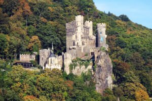 Rheinstein Castle perched on rocky cliff amid autumn forest