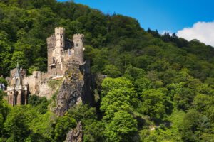 Rheinstein Castle perched on rocky Rhine cliff surrounded by forest