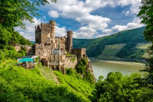Rheinstein Castle perched above the Rhine with lush hills and river