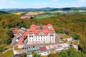 Aerial view of Bieberstein Palace, Hesse atop forested hill with red roofs