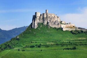 Spiš Castle ruins atop grassy hill under blue sky