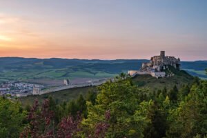 Spiš Castle on hilltop at sunset overlooking valley