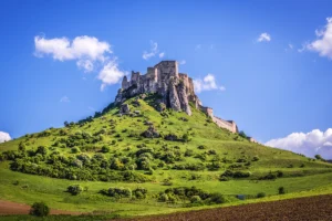 Spiš Castle ruins atop green hill under blue sky