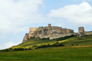 Spiš Castle ruins atop green hill beneath blue sky