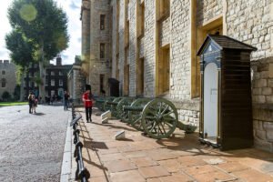 Guardsman beside historic cannons at The Tower of London courtyard