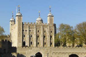 The Tower of London white stone keep and turrets against a clear blue sky