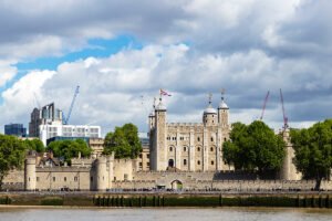 The Tower of London along the Thames, stone walls and towers under cloudy sky