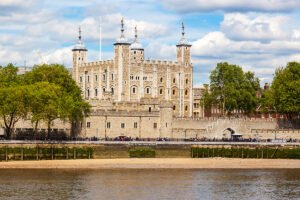 The Tower of London from across the Thames, stone walls and riverside path