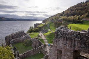 Ruins of Urquhart Castle on grassy promontory beside Loch Ness