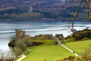 Urquhart Castle ruins on Loch Ness shore, visitors on path
