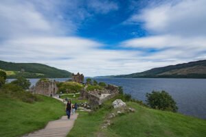 View of Urquhart Castle ruins beside Loch Ness with visitors on grassy path