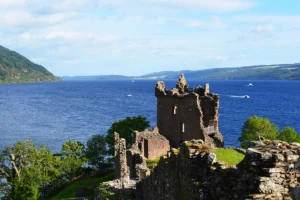 Ruined Urquhart Castle overlooking deep blue waters of Loch Ness