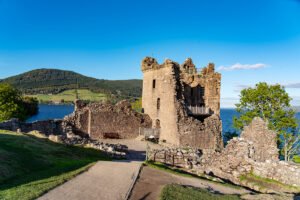 Ruined Urquhart Castle beside Loch Ness under blue sky