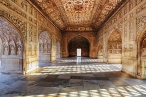 Sunlit marble hall interior at Agra Fort with carved arches