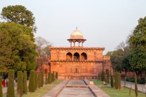 Agra Fort red sandstone facade with lawn and reflecting pool at sunset