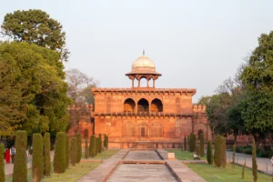 Agra Fort red sandstone facade with lawn and reflecting pool at sunset