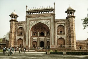 Visitors in front of Agra Fort ornate red sandstone gateway under pale sky