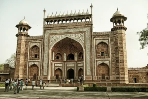 Visitors in front of Agra Fort ornate red sandstone gateway under pale sky