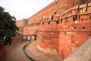Agra Fort exterior red sandstone walls and moat curve under hazy sky