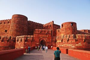 Visitors approaching Agra Fort red sandstone gate under clear sky