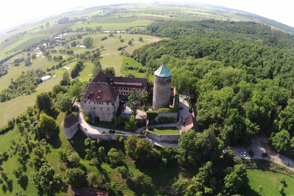 Aerial view of Burg Colmberg on wooded hill with surrounding farmland