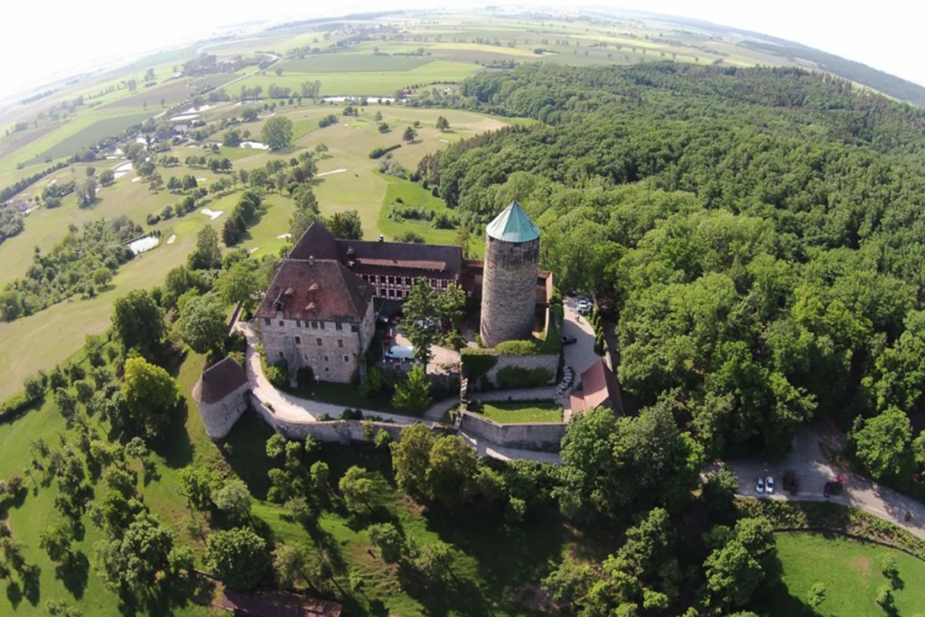 Aerial view of Burg Colmberg on wooded hill with surrounding farmland