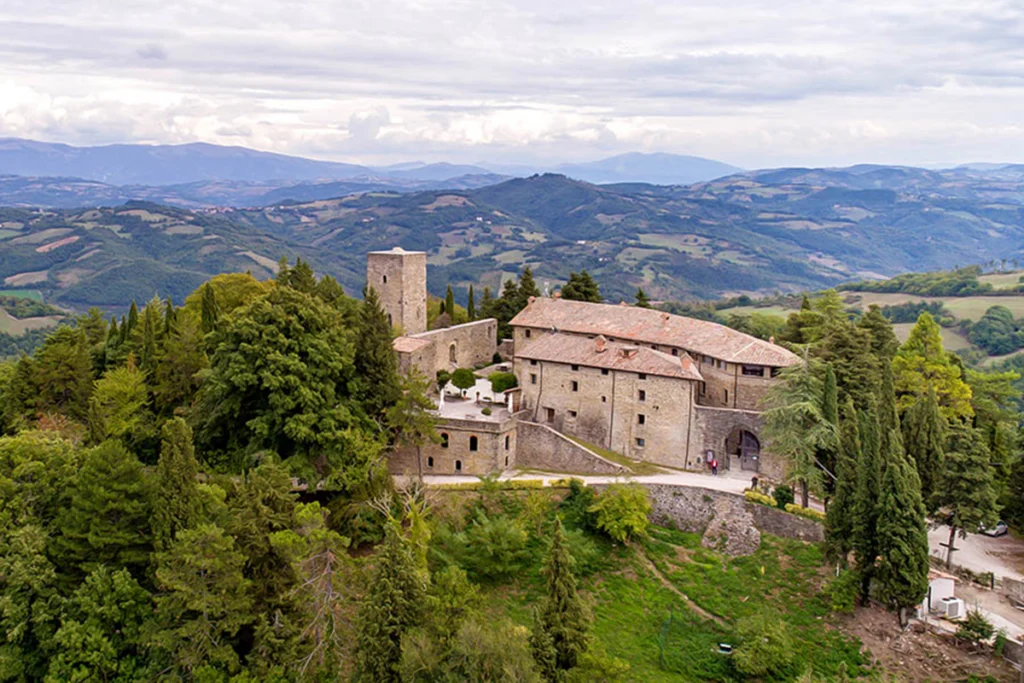 Aerial view of Castello di Petroia on wooded hill in Umbrian landscape