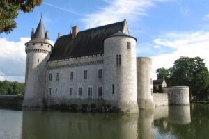 Moated stone castle reflected in calm water, Château de Sully-sur-Loire