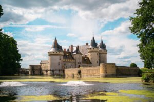 Moated Château de Sully-sur-Loire with round towers and wooden bridge under blue sky