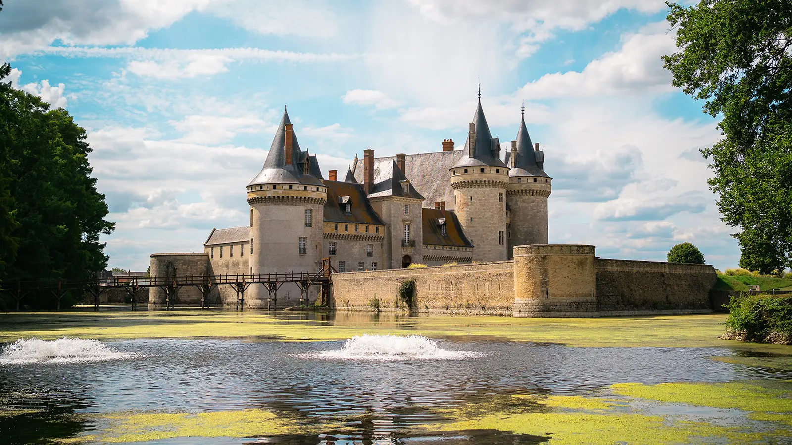 Château de Sully-sur-Loire by reflective moat under blue sky