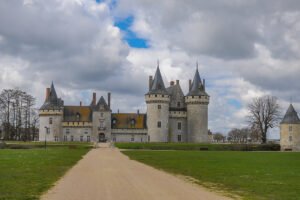Distant view of Château de Sully-sur-Loire with towers, moat, pathway and cloudy sky