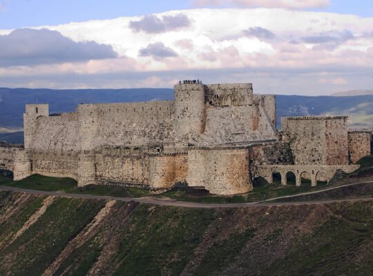 Krak des Chevaliers fortress on a hill under cloudy sky