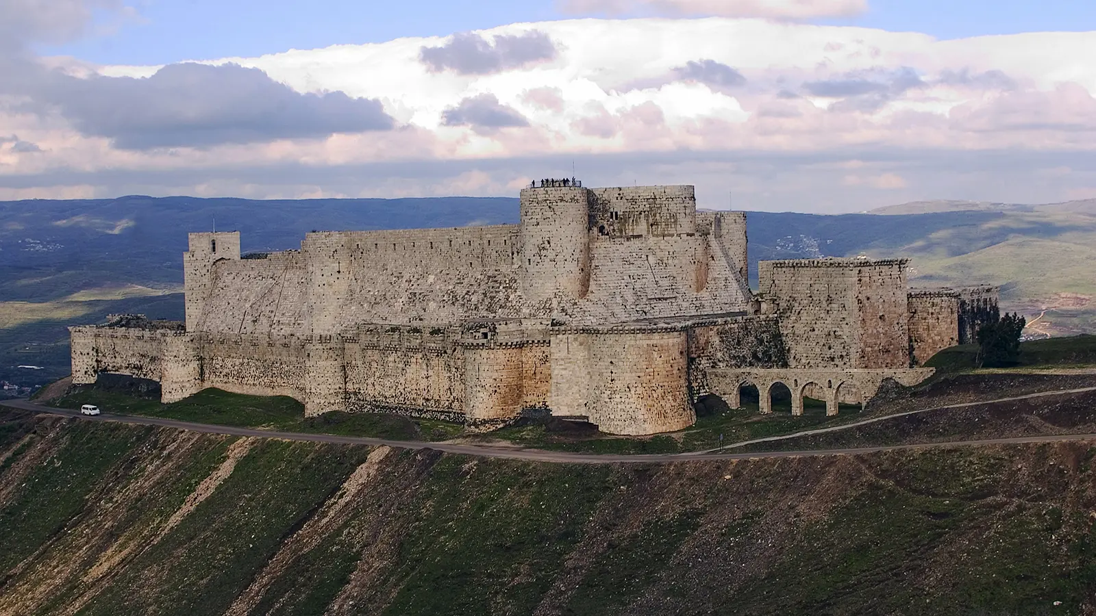 Krak des Chevaliers fortress on a hill under cloudy sky
