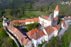 Aerial view of Krivoklat Castle on hilltop surrounded by forest