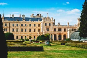 Lednice Castle facade with manicured formal gardens under blue sky