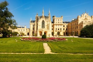 Lednice Castle facade and manicured gardens under blue summer sky