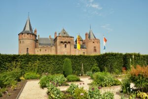 Muiderslot Castle with manicured gardens and towers under blue sky