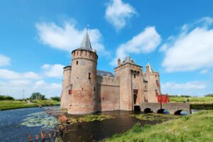 Muiderslot Castle reflected in moat with lily pads