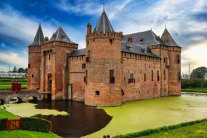 Muiderslot Castle beside green moat under cloudy sky