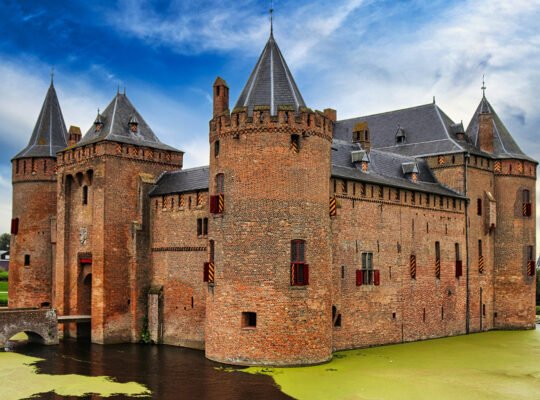 Muiderslot Castle across green moat under dramatic cloudy sky