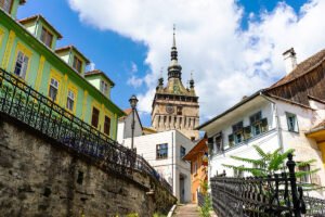 Sighișoara Citadel tower rising above colorful houses under blue sky