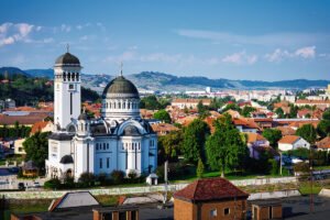 View of Sighișoara Citadel cathedral domes and red-roofed town under blue sky