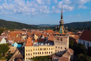 Aerial view of Sighișoara Citadel rooftops and clock tower against forested hills