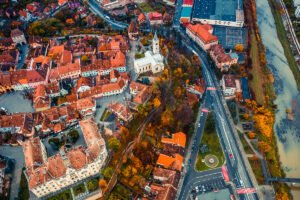 Aerial view of Sighișoara Citadel with red roofs, church and river