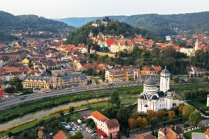 Aerial view of Sighișoara Citadel perched above colorful rooftops and river